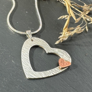 Silver open heart necklace with small copper heart
