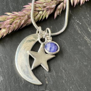 Silver necklace with a moon, star, and sapphire charm